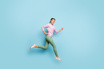 Full length photo of beautiful lady jumping high up rushing shopping mall speed race final season low prices wear casual pink sweater green pants isolated blue color background