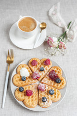 Homemade Belgian heart waffles with strawberry sauce and berries, pink flowers, spring, woman day morning concept, Valentine's day