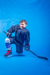 Obraz premium Young hockey player in black uniform before the game on a blue background