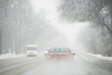 Fototapeta na wymiar The car is driving on a winter city street in a blizzard