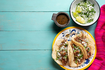 Mexican slow cooked lamb tacos also called barbacoa on turquoise background