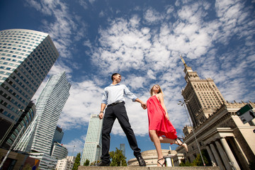 Bottom view of a young romantic couple. Woman in red dress walks holding hands with a man on the...