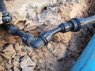 Black plastic plumbing pipe fitting. Compression PB pipe that connects the main plumbing and sub-plumbing. On the ground background. .grab lock fitting.Selective focus
