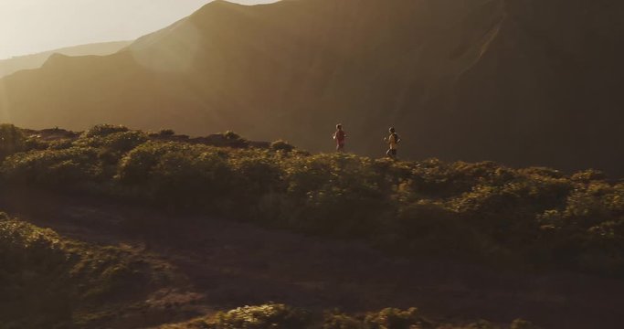 Aerial view of two adventurous runners exploring the mountains at sunset, friends running in the great outdoors at sunset