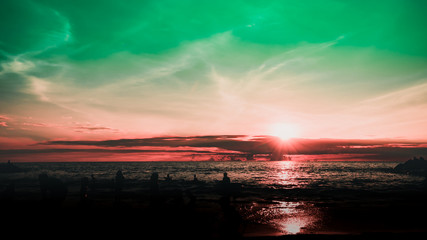 Obraz premium Dramatic sky and clouds on the beach at sunset. Silhouettes of people on the beach at sunset. City residents are enjoying a weekend by the sea. 
