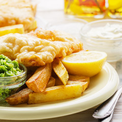 Traditional British street food fish and chips with tartar sauce and mushy peas on paper plate