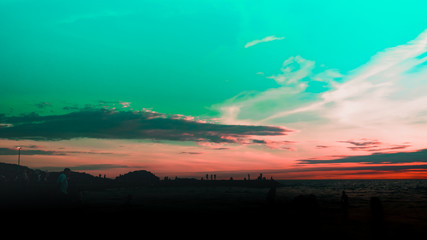 Dramatic sky and clouds on the beach at sunset. Silhouettes of people on the beach at sunset. City residents are enjoying a weekend by the sea. 