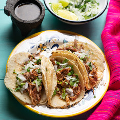 Mexican slow cooked lamb tacos also called barbacoa on turquoise background