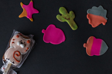 Making edible marzipan figures with your hands and cookie cutters to decorate baking. Ready-made and packed gingerbread on a black background.