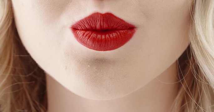 Close up shot of face of girl wearing bright red lipstick seductively biting lips and blowing kisses 4k footage