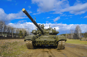 Russian armored tank in green camouflage against a blue blue sky. The gun looks menacingly to the top.