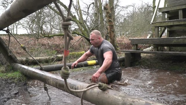 Man Climbing Out Of Cold, Muddy Water On A Mud Run / Obstacle / Assault Course - Super Slow Motion - Stock Video Clip Footage