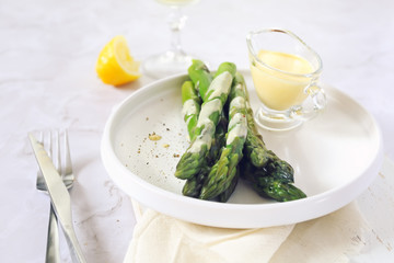 French cuisine. Fresh green asparagus with hollandaise sauce and glass of white wine