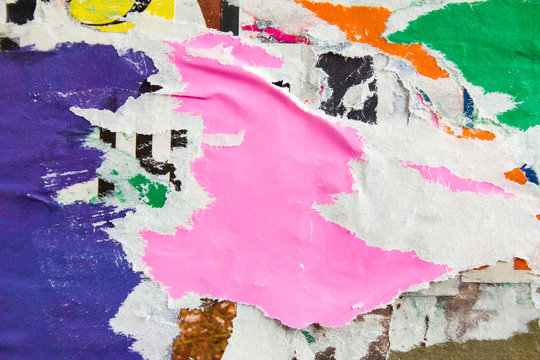 Pink and blue torn ripped and peeling urban paper posters and placards layers on dirty wall billboard texture background.