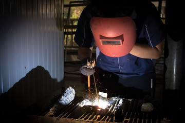  Mechanic student on steel structure in factory, light spark.