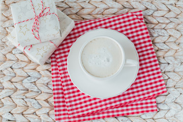 A cup of coffee or cappuccino and two gift boxes on white background.