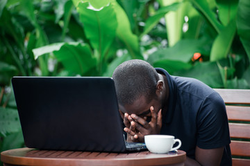 Serious pensive african businessman looking laptop in a coffee cafe