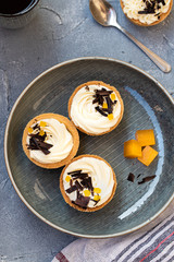 homemade shortbread tartlets or cupcakes with delicate cream and orange jam, decorated with chocolate chips. natural sweets concept. cozy tea party
