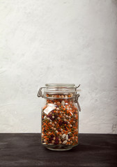 Beans, white and red, lentils green and red, peas in a closed glass jar on a black table on a white background. opy spaes.