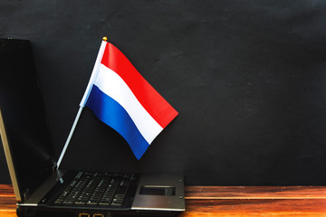  flag of Netherlands , computer, laptop on table and dark background