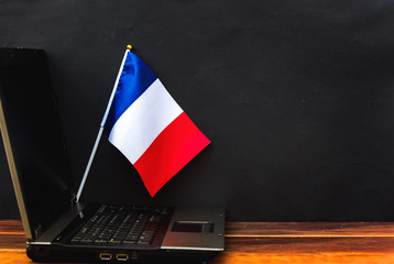  flag of France , computer, laptop on table and dark background