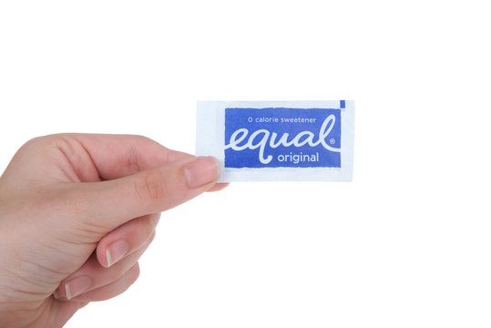Alameda, CA - September 18, 2017: Hand holding packet of equal artificial sweetener, isolated. Equal is an artificial sweetener containing aspartame, acesulfame potassium, dextrose and maltodextrin