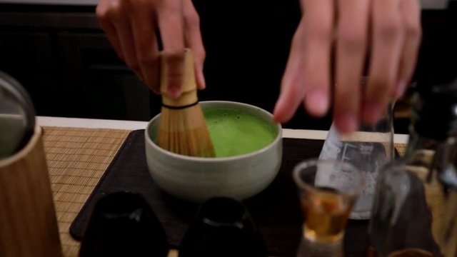 Matcha green tea making by stir the tea then put some milk in a cup in Japanese style
