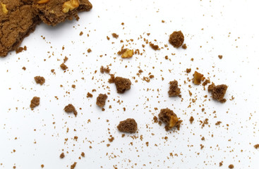 Cookies of chocolate chip butter flavored bitten with scattered crumbs on white background.