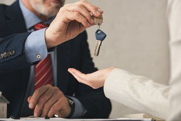 cropped view of realtor giving key to woman in office