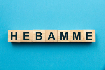 Reihe aus Holzwürfeln mit dem Wort Hebamme auf blauem Hintergrund
