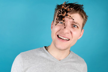 Young shocked guy with a spider on his head