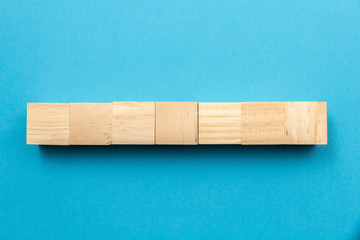 seven wooden toy cubes arranged in row on a blue background