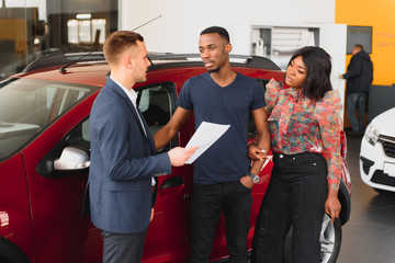 happy woman receiving a new car from her husband at dealership