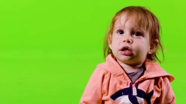 Close up of a cute toddler, laughing and smiling over green screen.