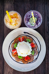 waffles with chocolate sauce, ice cream and strawberries and Kiwi on wood background