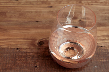 vaso para vino sobre fondo de madera con colores dorados en la base, piso de madera