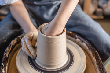 Potter working on a Potter's wheel making a vase. Woman forming the clay with hands creating jug in a workshop. Close up