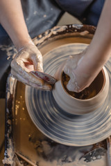 Potter working on a Potter's wheel making a vase. Woman forming the clay with hands creating jug in a workshop. Top view