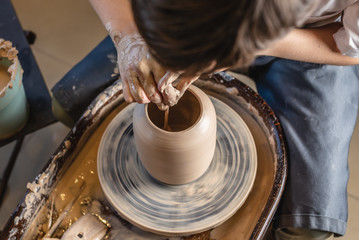 Potter working on a Potter's wheel making a vase. Master processing the formed jug giving it the correct shape