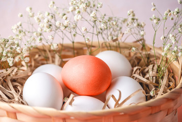 Bright red Easter egg among white ones in a basket on a light background. Festive spring card