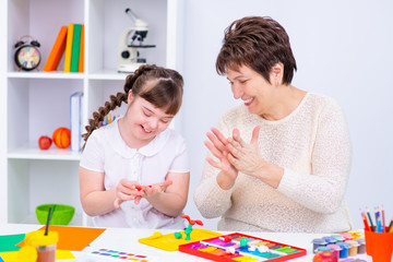 Girl with Down Syndrome works with her teacher at home