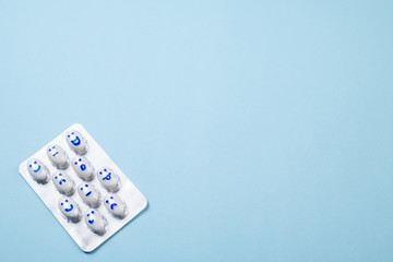 Blister of funny pills with smiles faces on blue background. Health care, daily pills, antidepressants, medicine, treatment concept. Copy space