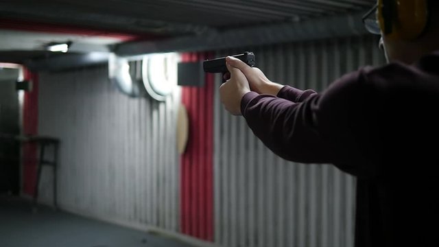Shooting gallery. A young man shooting with a firearms. A smoking gun