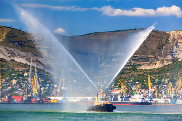 Floating tug boat is spraying jets of water, demonstrating firefighting water cannons