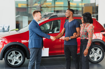 young african couple buying new car at dealership