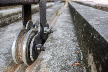 Dirty rusty steel roller wheels of sliding gates on concrete floor.