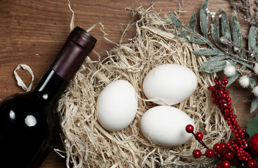 Wine red bottle and chicken eggs in hay.  