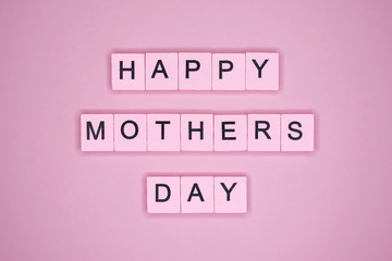 Happy mothers day, words wooden cubes on a pink background