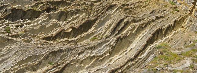 Photography of the rock texture. Detail of cliff in Zumaia in Basque Autonomous Community / country in summer cloudy day in Bay of Biscay. Ornamental pattern of mountain surface. High resolution image