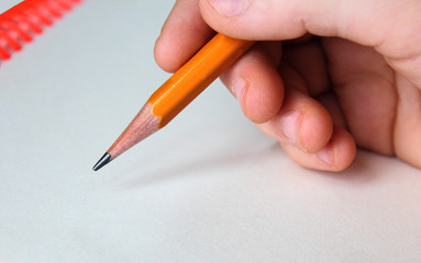 Close-up child hand holding a pencil on white background.